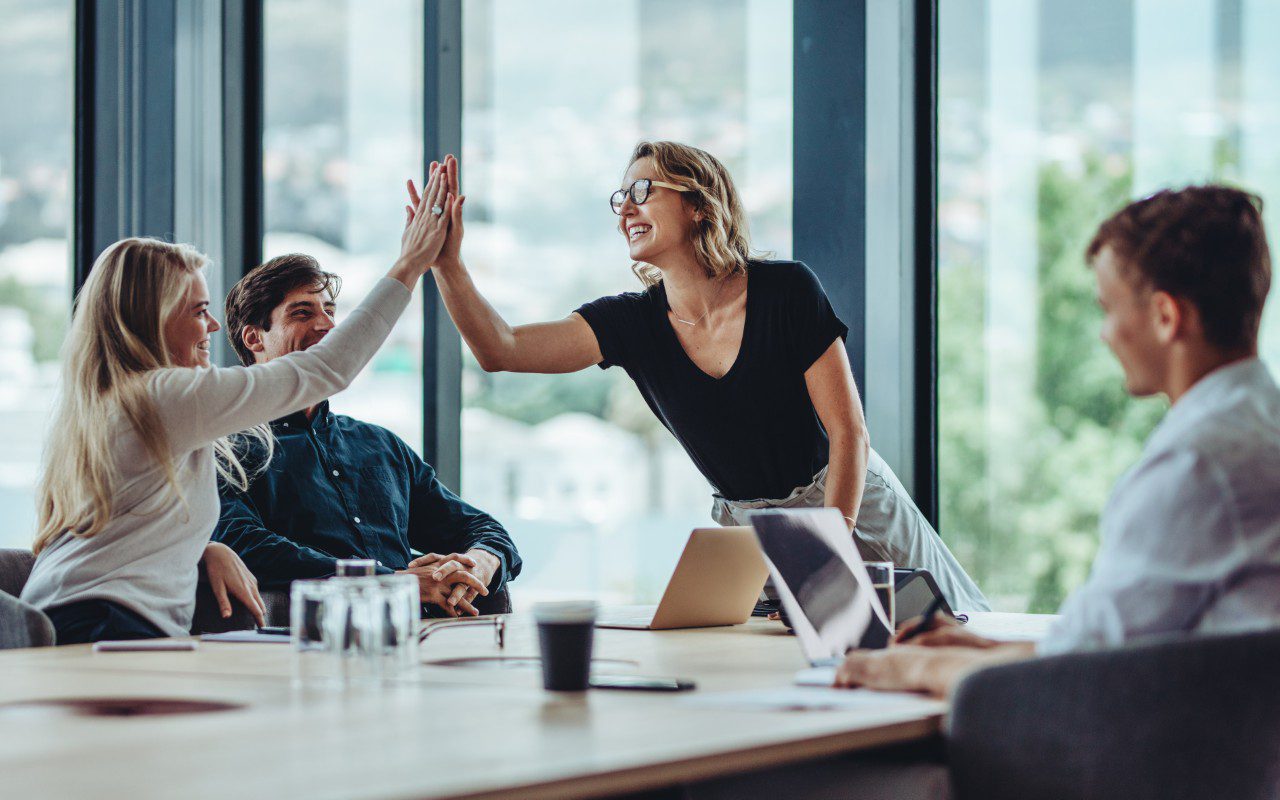 Team celebrating with a high-five in office.