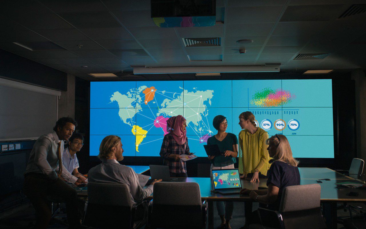 People discussing in front of world map.